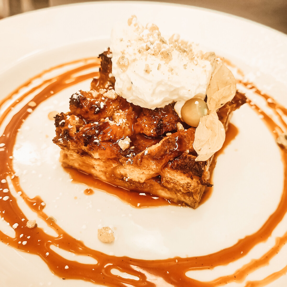 plated pumpkin bread pudding with a dollop of chantily cream and circles by caramel sauce